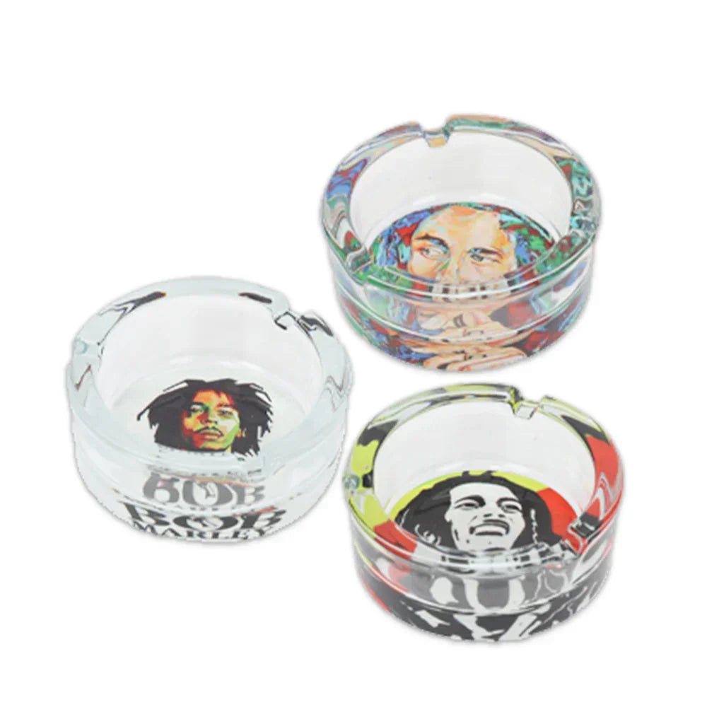 Clear glass ashtrays featuring colorful Bob Marley portraits and reggae-themed designs