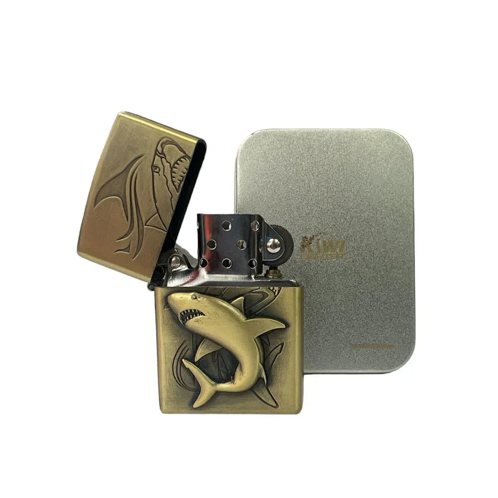Brass lighter with 3D shark design, opened lid, next to silver metal case on white background