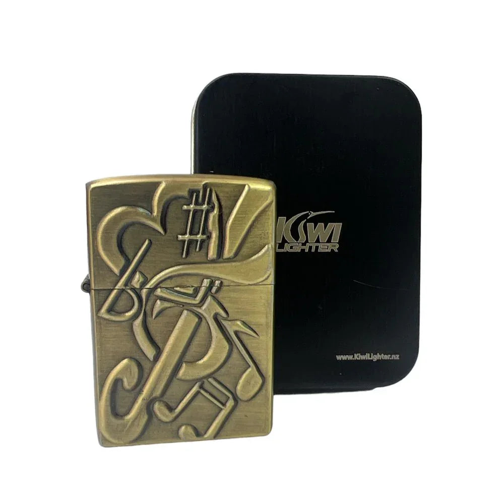 Brass-colored music notes engraved lighter with black Kiwi Lighter box in background