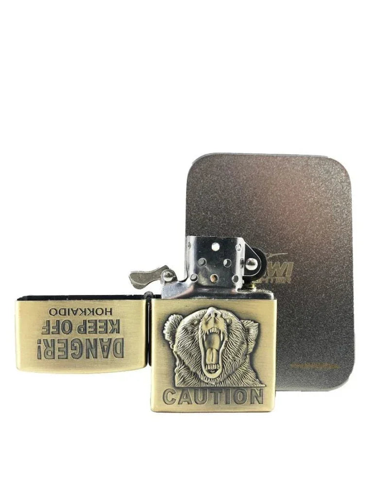Brass flint lighter with open lid featuring roaring bear engraving and caution warning