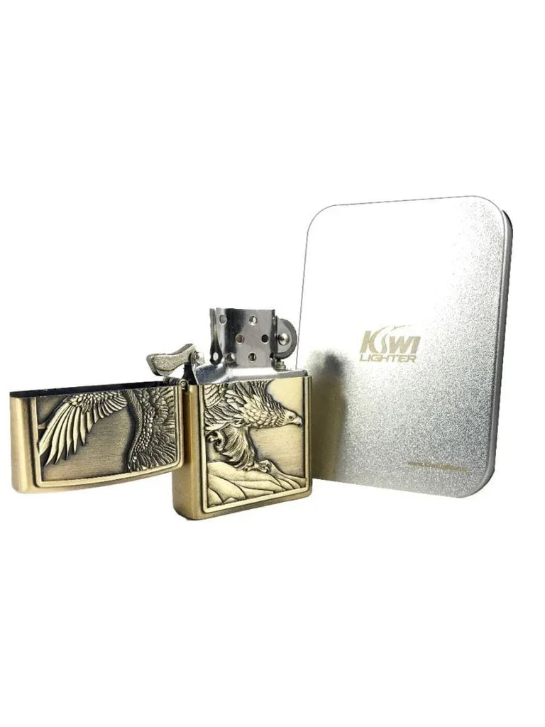 Brass metal lighter with engraved soaring eagle design next to silver Kiwi lighter tin box