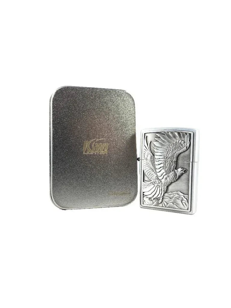 Silver lighter with embossed eagle design next to textured grey metal case on white background