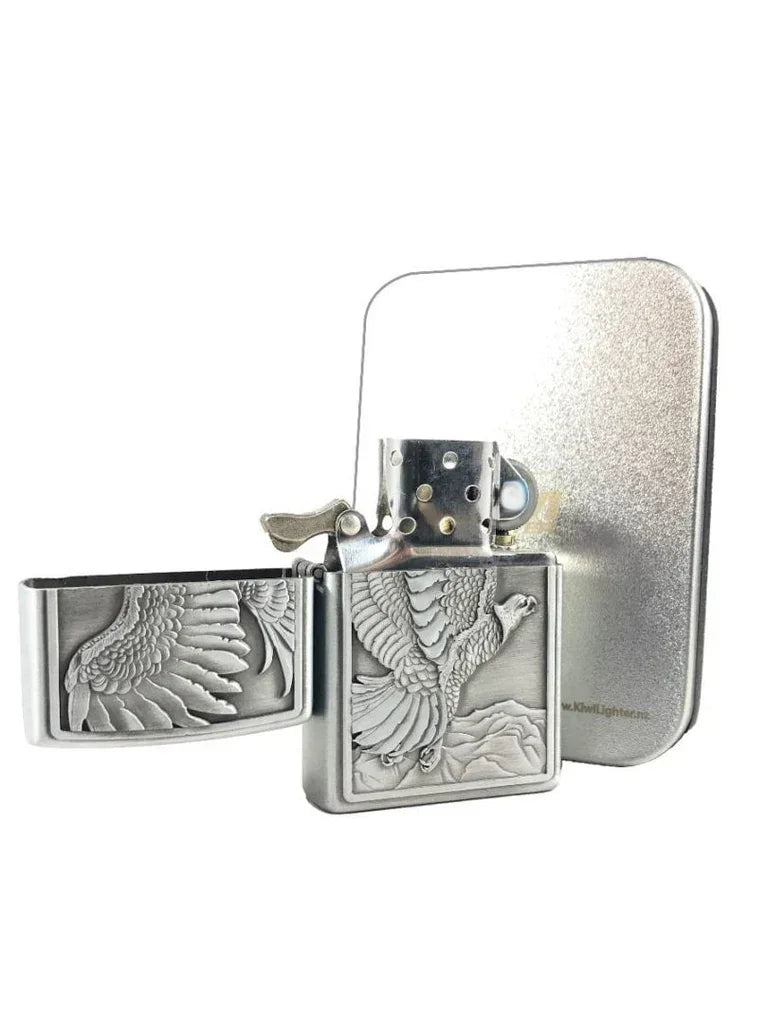 Silver metal flip-top lighter with embossed eagle design flying over mountains, displayed open with matching silver case
