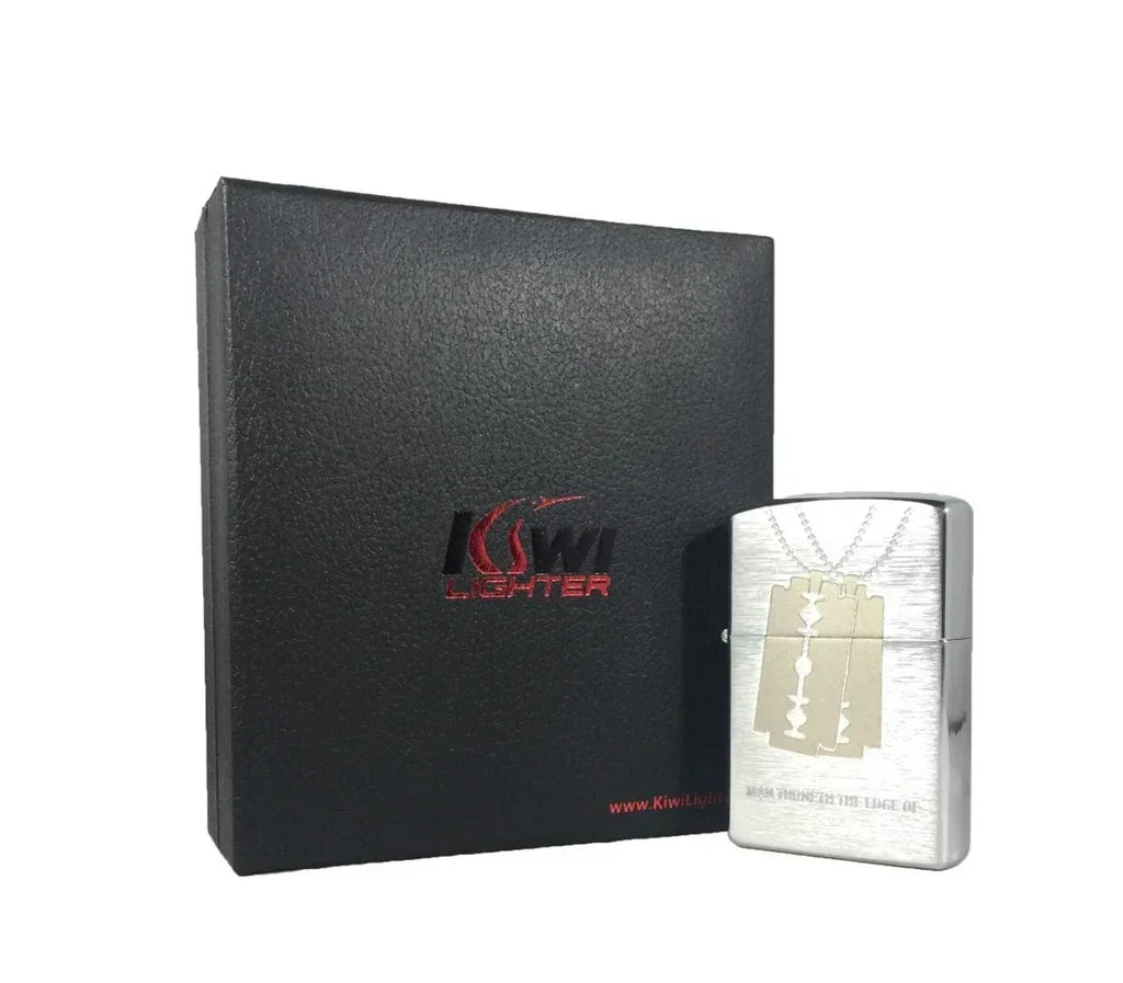 Silver Kiwi-brand metal lighter with razor blade design, next to black textured gift box