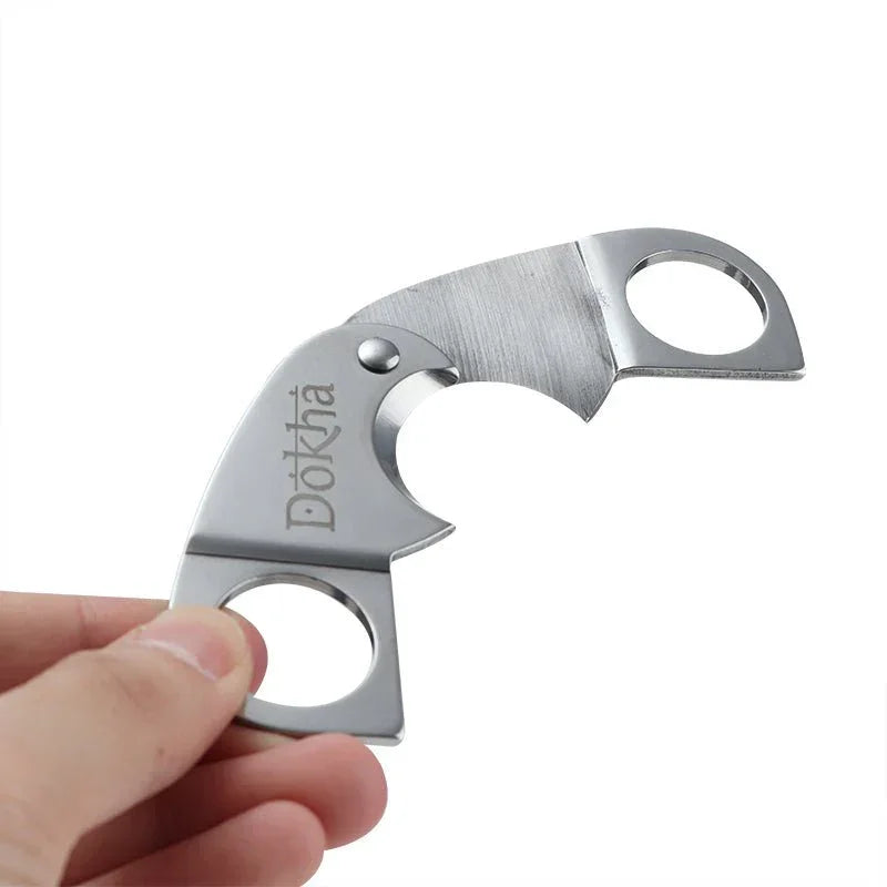 Hand holding a compact stainless steel folding knife with two finger holes and Dökhä engraving